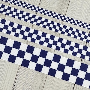 May include: Four strips of grosgrain ribbon arranged in parallel, each featuring a repeating navy blue and white checkered pattern. The ribbons vary in width, with the thinnest at the top and the widest at the bottom, all displaying a ribbed texture.