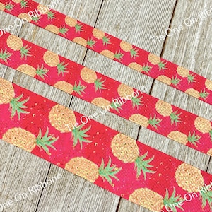 May include: Three rolls of red ribbon with a gold pineapple print. The pineapples have green leaves and are on a red background with gold glitter.