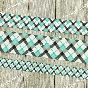 May include: Three rolls of plaid ribbon in white, black, and light blue. The ribbon has a diamond pattern.