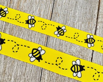 May include: Yellow ribbon featuring a repeating pattern of cartoon bees and dotted flight paths. The bees are black and yellow with white detailing. Suitable for crafting and decorative use.