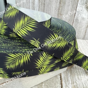May include: A roll of black and green ribbon with a tropical leaf pattern. The ribbon is made of grosgrain and has a shiny finish.