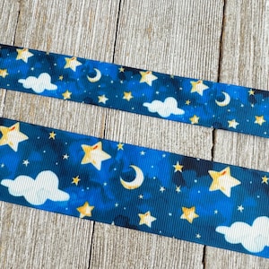 Puede incluir: Cinta azul y blanca con un patrón de cielo nocturno con estrellas amarillas, una luna creciente y nubes blancas.