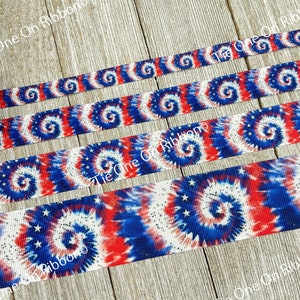 May include: Red, white, and blue tie dye ribbon with white stars. The ribbon has a glittery finish.