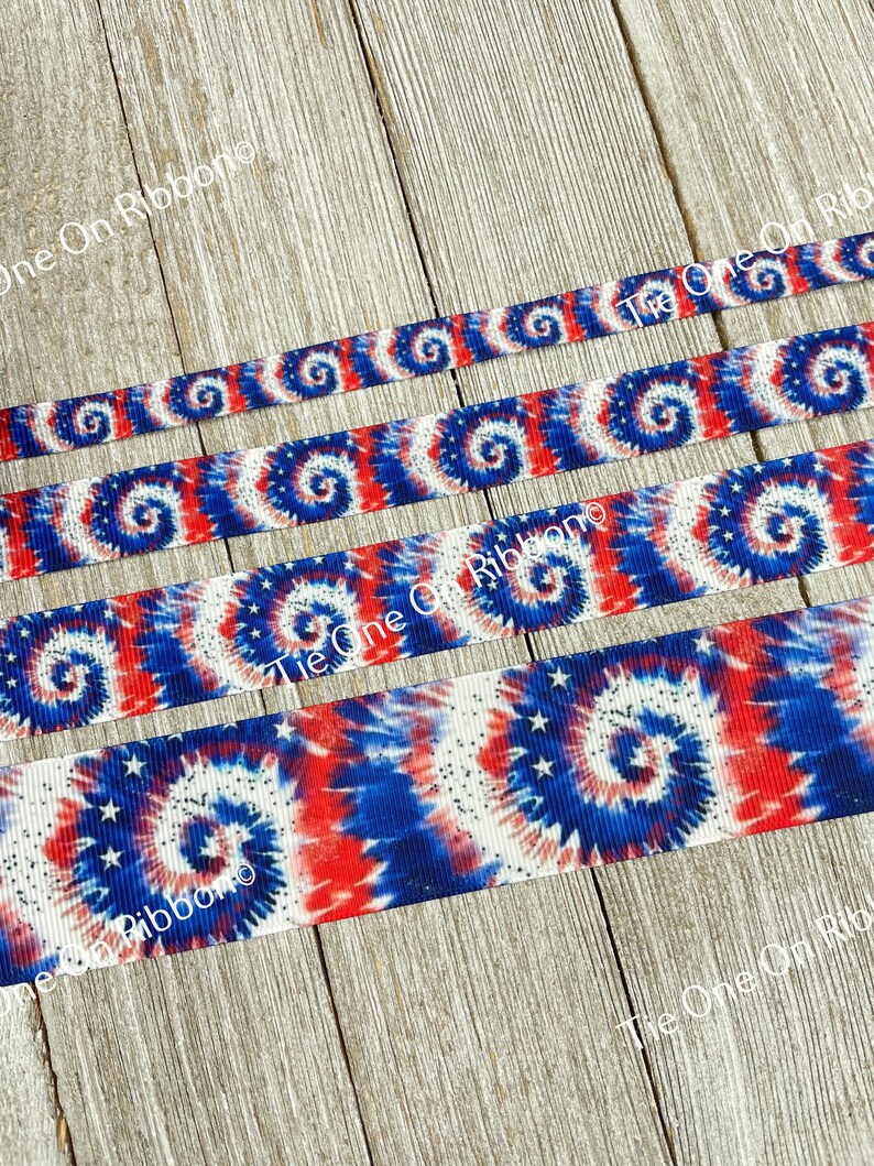 May include: Red, white, and blue tie dye ribbon with white stars. The ribbon has a glittery finish.