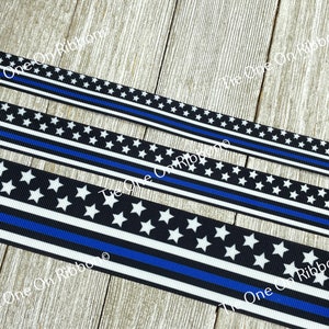 May include: Black and white ribbon with a thin blue line and white stars. The ribbon is on a wooden surface.