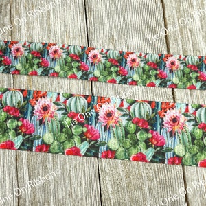 May include: A close-up of a colorful ribbon with a cactus and flower print. The ribbon is on a wooden surface.