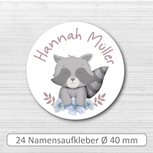 Könnte beinhalten: Ein weißer runder Aufkleber mit einer rosa Waschbär-Illustration und dem Text "Hannah Müller" in rosa. Der Aufkleber hat einen Durchmesser von 40 mm.