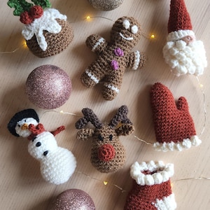 Puede incluir: Una colección de adornos navideños hechos a mano en crochet, que incluyen un hombre de jengibre, un reno, un muñeco de nieve, una media y un Papá Noel. Los adornos están hechos con varios colores de hilo, incluyendo rojo, blanco, marrón y verde.