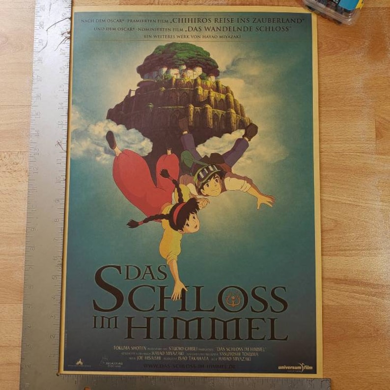 May include: A vintage movie poster for the animated film "Castle in the Sky" (Japanese: "Laputa: Castle in the Sky"). The poster features a scene of two characters falling from the sky, with a floating castle in the background. The text on the poster reads "Das Schloss im Himmel" (German for "Castle in the Sky").
