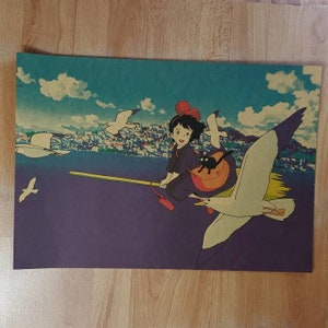 May include: A vintage-style poster featuring a young woman with red hair and a black cat flying on a broomstick with a seagull. The background is a colorful cityscape with a blue sky and white clouds.