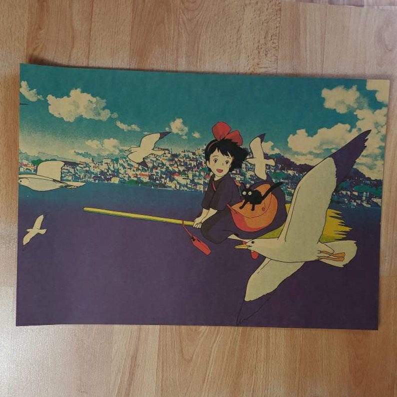 May include: A vintage-style poster featuring a young woman with red hair and a black cat flying on a broomstick with a seagull. The background is a colorful cityscape with a blue sky and white clouds.