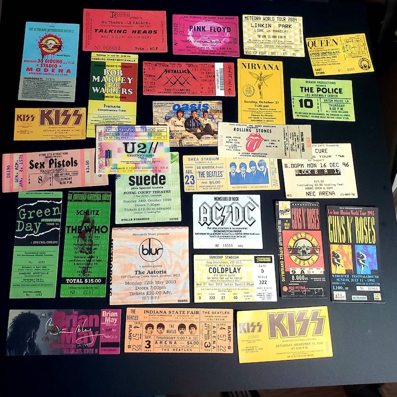 K&ouml;nnte beinhalten: Eine Sammlung von Vintage-Konzertkarten mit verschiedenen K&uuml;nstlern, darunter KISS, The Beatles, Green Day, U2 und Guns N' Roses. Die Tickets werden auf einer schwarzen Oberfl&auml;che angezeigt und weisen eine Vielzahl von Farben, Schriftarten und Designs auf.