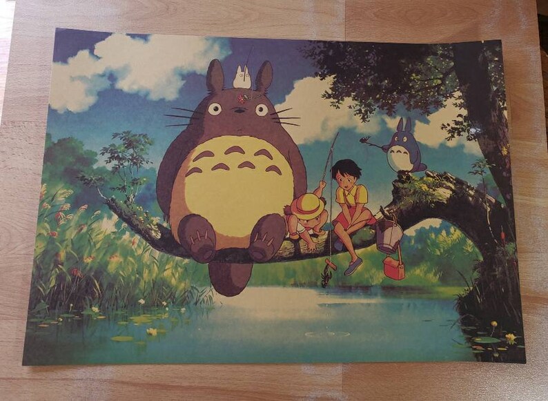 May include: A whimsical illustration of a large, furry, gray and yellow creature with big eyes, sitting on a tree branch with two children fishing in a pond. The creature is surrounded by lush green foliage and a blue sky with white clouds.