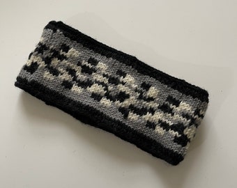 May include: A black, white, and gray knitted headband with a geometric pattern.