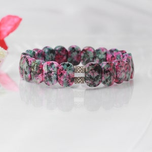 Op de afbeelding: Een armband van roze en groene edelstenen met zilveren accenten. De armband is gemaakt van ovale kralen en heeft een sluiting.