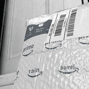 May include: A white padded envelope with the Amazon Prime logo and the text "fast, free delivery" and "prime". The envelope has the text "rain" and "barrel" printed on it.