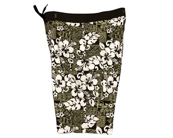 May include: Brown swim trunks with a white and green floral print. The print features hibiscus flowers and geometric patterns.