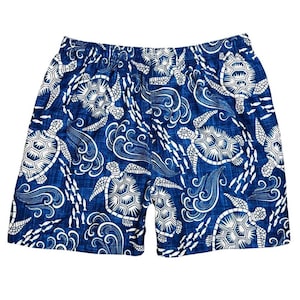 May include: Blue swim trunks with a white turtle and wave pattern. The shorts feature an elastic waistband and a repeating design of turtles, fish, and ocean waves. The fabric has a textured appearance.