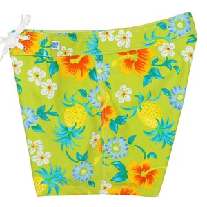 May include: Green swim shorts with a tropical print featuring pineapples, hibiscus flowers, and other floral designs.