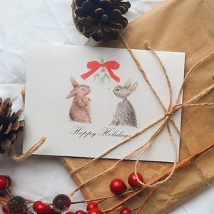 Simpatico biglietto di Natale con conigli sotto il vischio, vuoto all'interno, perfetto da inviare alla famiglia nel periodo natalizio
