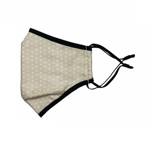 May include: A beige face mask with white polka dots and black elastic straps.