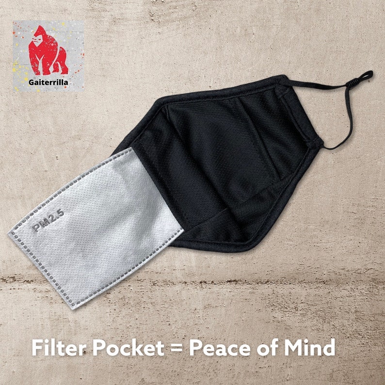 Peut inclure: Masque facial noir avec une poche &agrave; filtre. La poche &agrave; filtre est ouverte et un filtre blanc PM2.5 est visible. Le texte "Filter Pocket = Peace of Mind" est imprim&eacute; sous le masque.