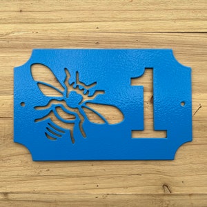 May include: Blue metal house number sign with a bee cutout and the number 1.