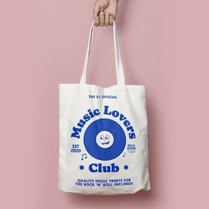 Peut inclure: Sac fourre-tout en toile blanche avec du texte bleu et un graphique de disque vinyle bleu. Le texte indique "The #1 Official Music Lovers Club Est 2020" et "Quality Music Prints for the Rock 'n' Roll Inclined!"