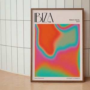 May include: A poster featuring an abstract design in shades of pink, orange, yellow, green, and blue. The poster has the word "IBIZA" in black text at the top and the text "Balearic Islands, Spain" in smaller black text below. The poster also includes the coordinates "38.9250° N 1.4329° E" at the bottom.