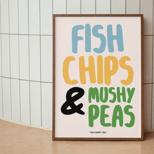 May include: A framed print with the text "Fish Chips & Mushy Peas" in colourful, playful lettering. The text is on a light pink background with a brown frame. The text "The Chippy Tea" is in smaller letters below the main text.