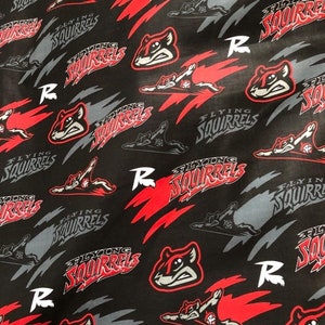 May include: Black fabric with a repeating pattern of red and gray flying squirrels. The squirrels are in a flying pose with the text "Flying Squirrels" written in red and gray. The letter "R" is also repeated throughout the pattern.