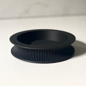 Könnte beinhalten: Eine schwarze, runde, 3D-gedruckte Schale mit einem strukturierten, gewellten Rand.