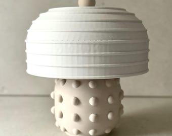 May include: A white ceramic lamp with a pleated lampshade and a textured base with raised dots.