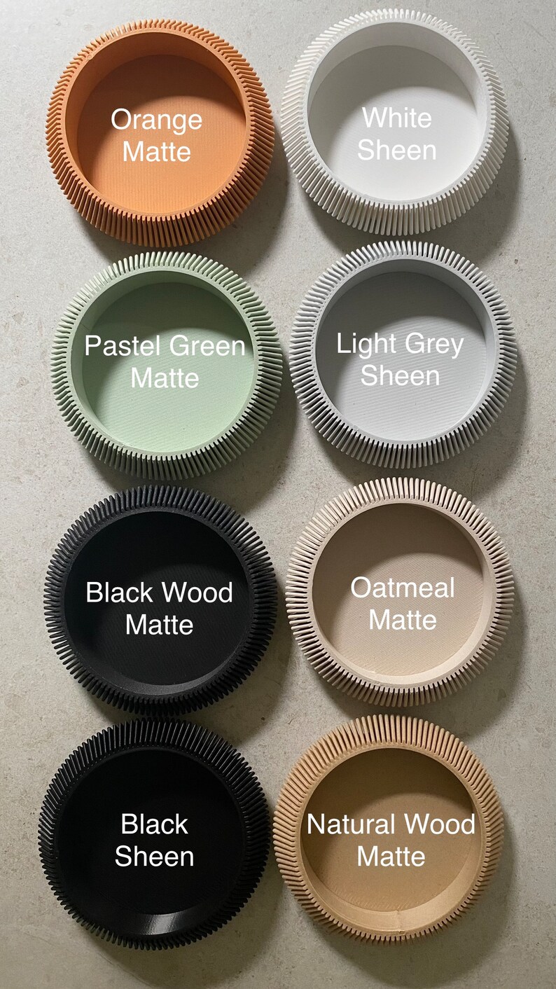May include: Eight round, decorative containers with a textured, ridged edge. The containers are in various colors and finishes, including orange matte, white sheen, pastel green matte, light grey sheen, black wood matte, oatmeal matte, black sheen, and natural wood matte.