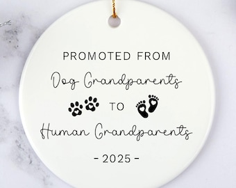 May include: White ceramic Christmas ornament with black text that reads "Promoted from Dog Grandparents to Human Grandparents - 2025 -" with paw prints and footprints.