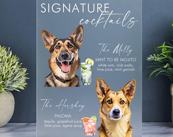 May include: A clear acrylic sign with the text "SIGNATURE cocktails" at the top. The sign features two dogs, one with a mojito and the other with a paloma. The text below each dog describes the cocktail.