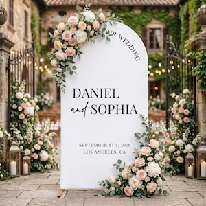 Può includere: Un cartello nuziale bianco ad arco con il testo OUR WEDDING, DANIEL and SOPHIA, SEPTEMBER 8TH, 2026 e LOS ANGELES, CA. Il cartello è decorato con composizioni di rose rosa e bianche e foglie di eucalipto verde nella parte superiore e inferiore.