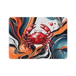 May include: A rectangular decorative piece featuring a red geometric crab design with the word "July" and the text "Your name". The background has an abstract design with orange, blue, and white swirls. Silver hardware is visible.