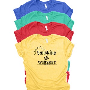 Può includere: Quattro t-shirt di diversi colori, giallo, rosso, verde e blu, con la scritta "Sunshine and Whiskey" stampata sulla t-shirt gialla.