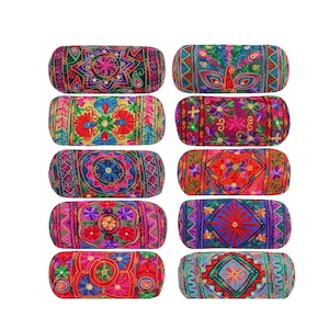May include: Set of ten colorful cylindrical throw pillows with embroidered floral and geometric patterns. The pillows are made of fabric and have a red, pink, blue, green, and yellow color scheme.