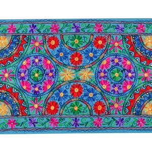 May include: A blue fabric wall hanging with a colorful embroidered design featuring a repeating pattern of flowers and circles.