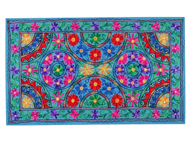 May include: A blue fabric wall hanging with a colorful embroidered design featuring a repeating pattern of flowers and circles.