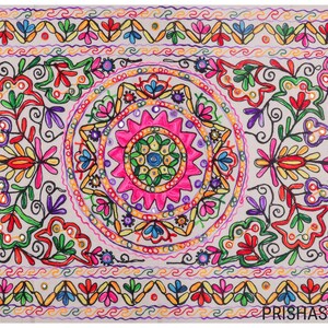 May include: A white cotton throw pillow with colorful embroidery featuring a floral design and a central circular pattern. The embroidery includes pink, green, blue, yellow, and orange thread.