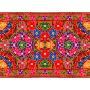 May include: A colorful embroidered throw pillow with a geometric pattern of circles and flowers in shades of red, orange, yellow, green, blue, and purple. The pillow is surrounded by a border of smaller flowers.