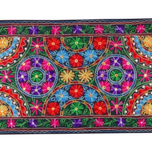 May include: A colorful embroidered tapestry with a black background featuring a repeating pattern of floral motifs and circular designs. The tapestry is made with a variety of colors, including red, pink, blue, green, and yellow.