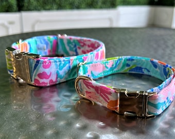 May include: Two dog collars with a floral pattern in shades of pink, blue, and green. The collars have gold metal buckles.