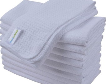 Puede incluir: Una pila de diez paños de limpieza de microfibra blancos con una etiqueta verde y azul que dice "Sunland" en el paño superior.