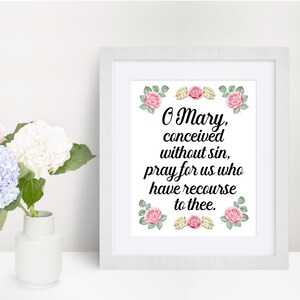 May include: A white framed print with a floral border and the text "O Mary, conceived without sin, pray for us who have recourse to thee."