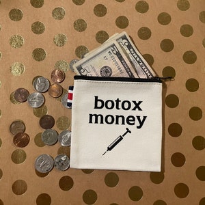 May include: White canvas coin purse with a black zipper and the text "botox money" printed in black. A syringe graphic is below the text. The purse is partially open and has dollar bills inside.
