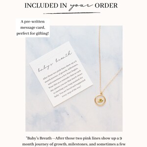 May include: A gold-toned necklace with a circular pendant containing a small white flower, accompanied by a square white card featuring the text: Baby's Breath --After those two pink lines show up a 9 month journey of growth, milestones, and sometimes a few fears begins.
